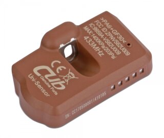 Das Bild zeigt ein braunes rechteckiges Gerät mit abgerundeten Kanten und einer Öffnung in der Mitte, auf dessen Oberfläche mehrere weiße Aufschriften zu sehen sind, darunter „Cub Genuine Parts Uni-Sensor“, technische Daten wie „433MHZ“ sowie verschiedene Nummern und Symbole.